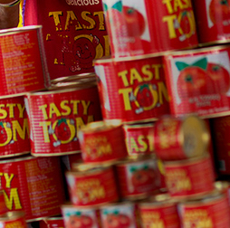 A stack of Tasty Tom tins full of tomato paste, Olam also manufactures pasta, biscuits, yoghurt drinks and edible oils for African markets.